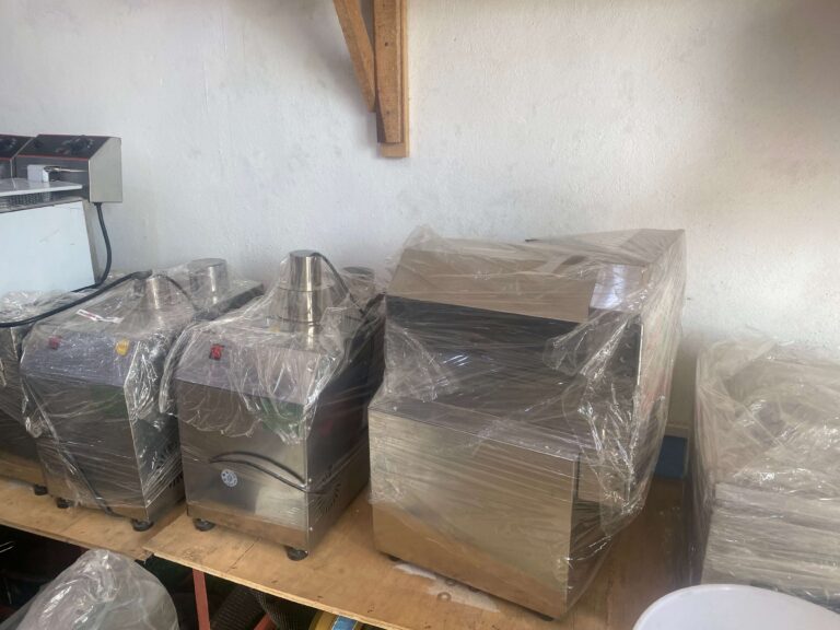 New stainless processing machines, still in their plastic wrap, on a bench