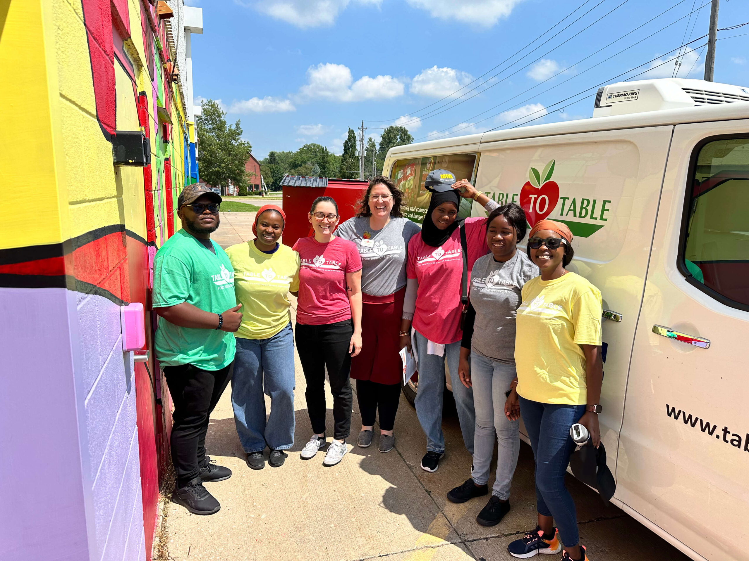 Mumita staff and partners stand beside a farm-to-table delivery van