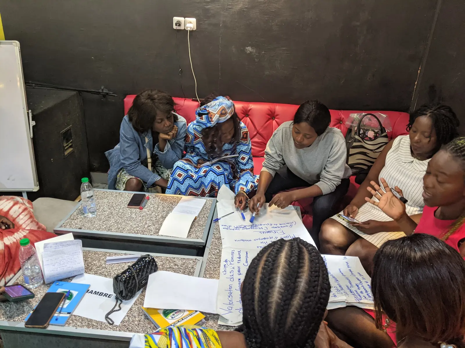 Women work on flip-chart sheets around a low table at a workshop