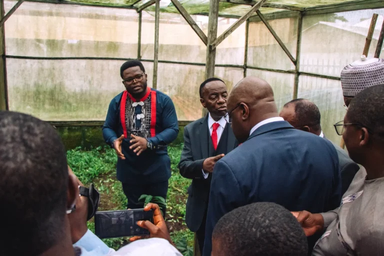 A Mumita team member shows visiting officials a greenhouse plot