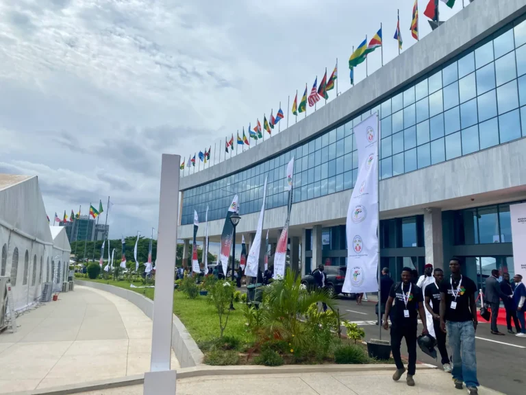 Delegates walk past a row of national flags outside the Biashara Afrika 2026 venue in Lomé