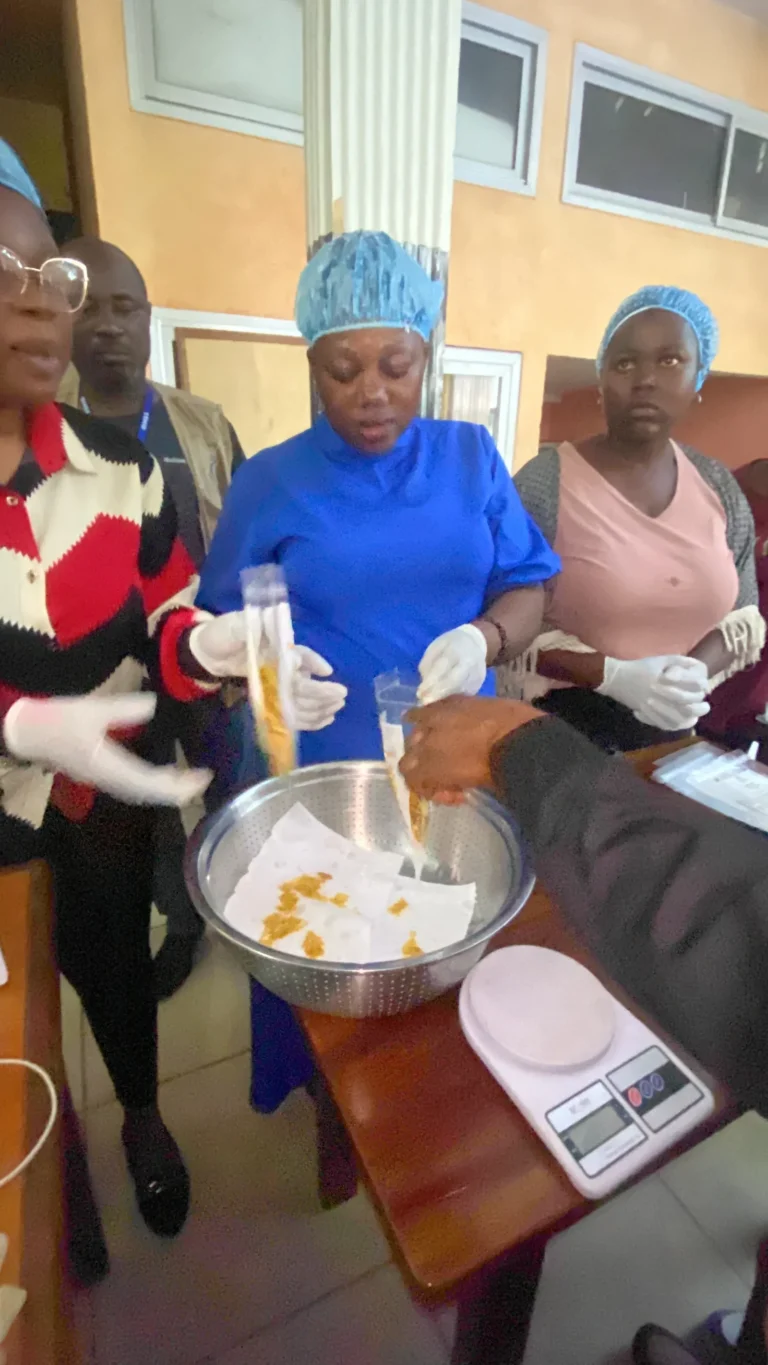 Trainees weigh plantain chips on a kitchen scale