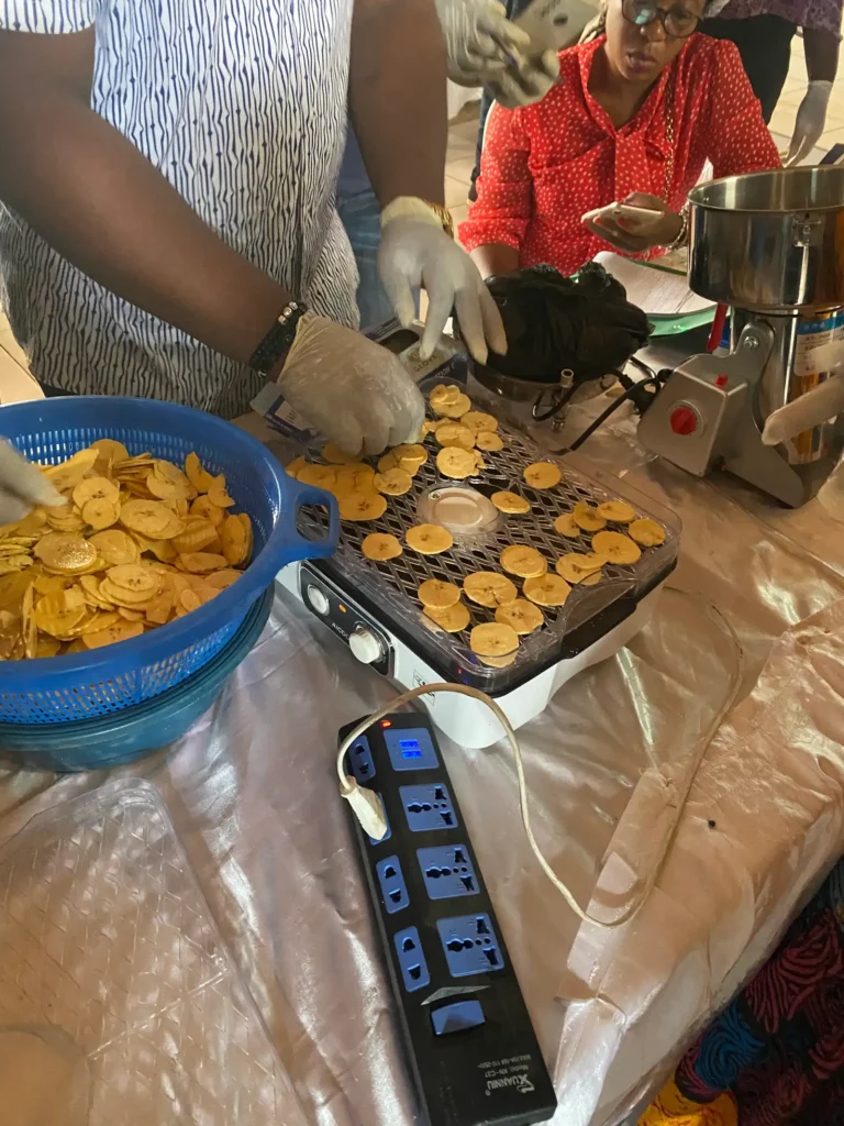 Gloved hands arrange plantain slices on a grill