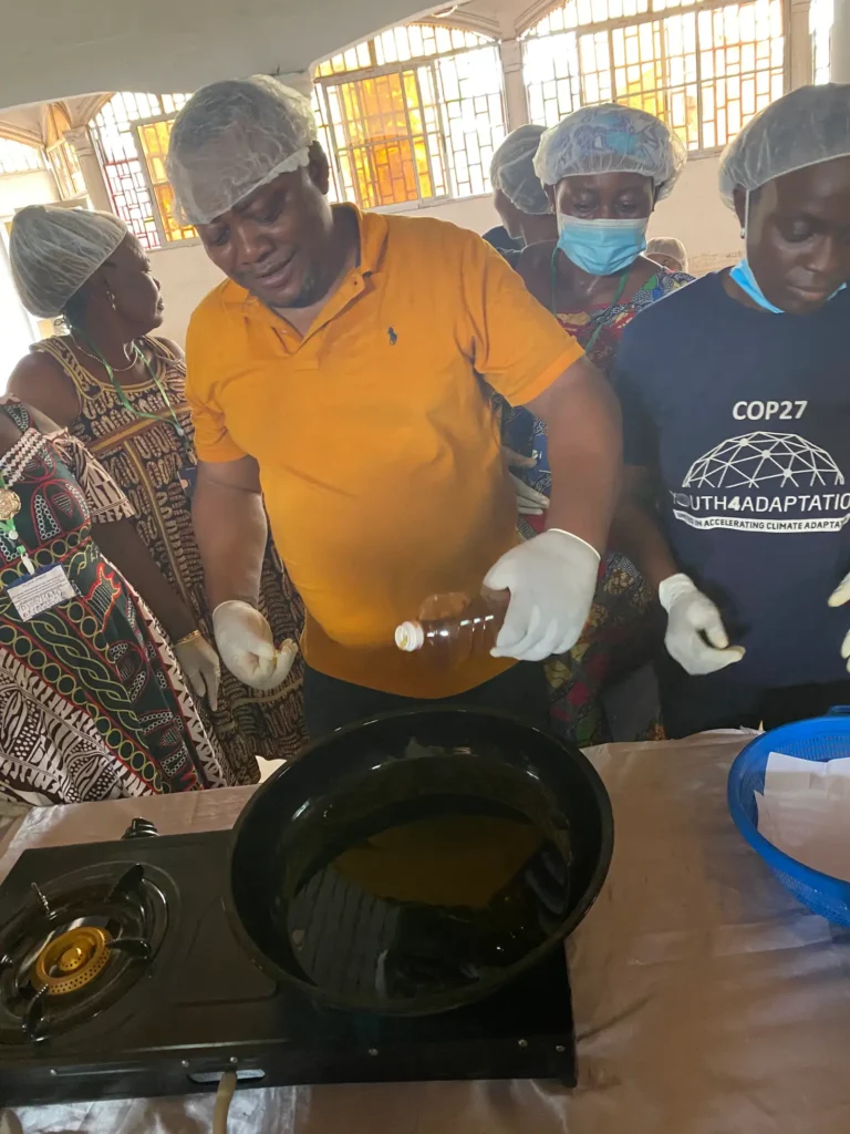 A trainer pours oil into a wok while trainees watch