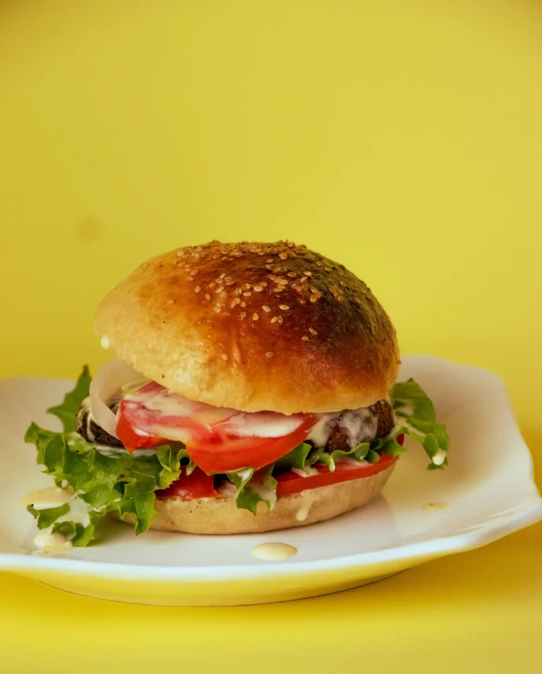 A Praïs burger with tomato and lettuce on a white plate