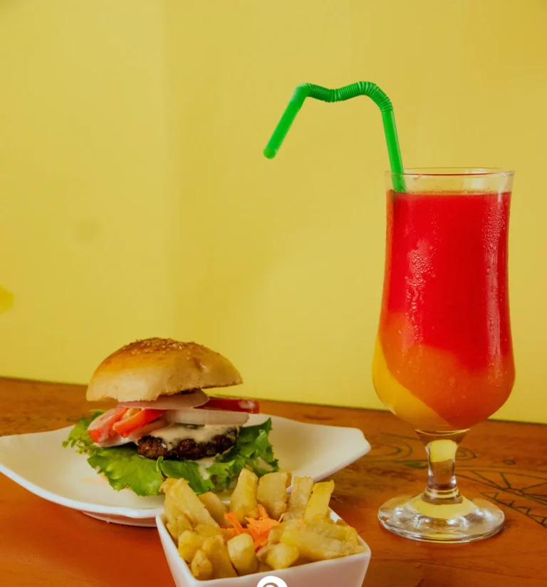 A burger with fries and a layered fruit juice