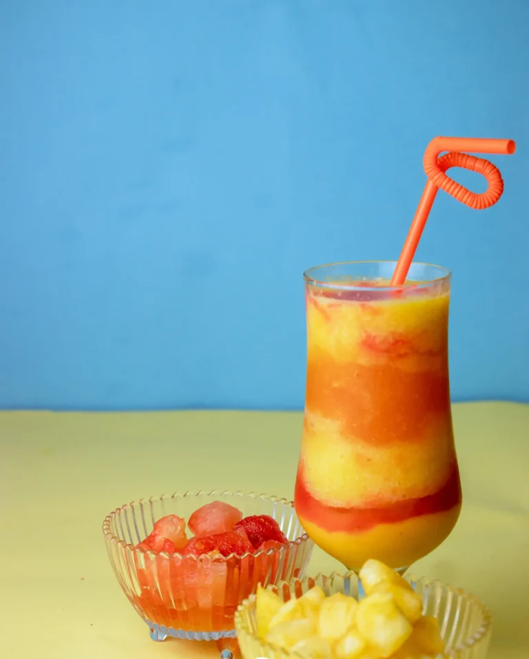 A mango smoothie with cups of fresh fruit