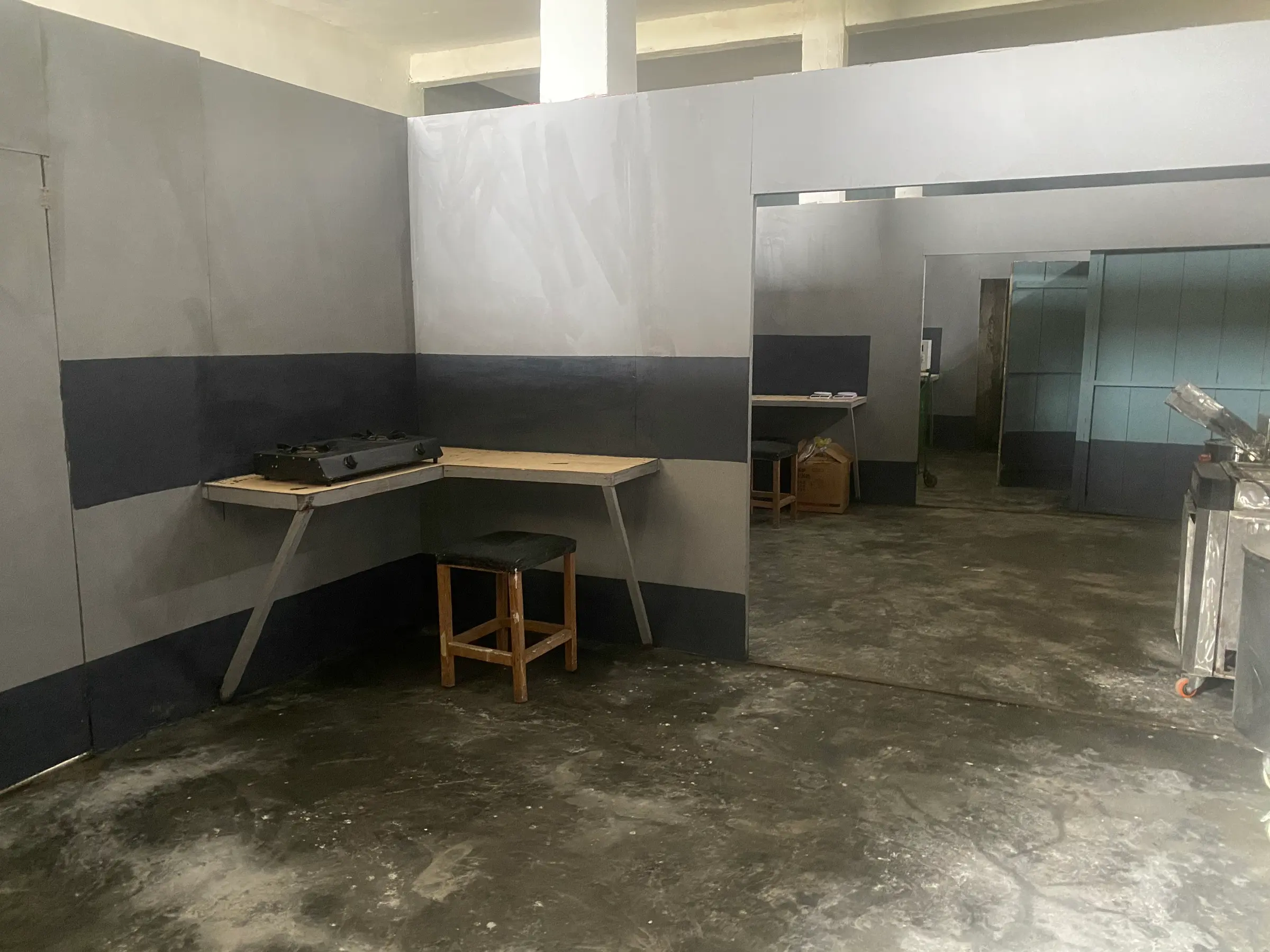 A painted processing room with a bench and stool, and a doorway into the next room