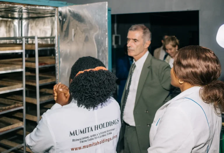 A staff member in a Mumita Holdings coat stands beside the drying cabinet with visitors