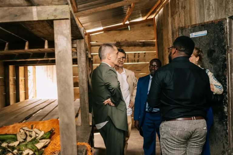 Visitors in a timber drying shed, with produce spread to dry on the floor