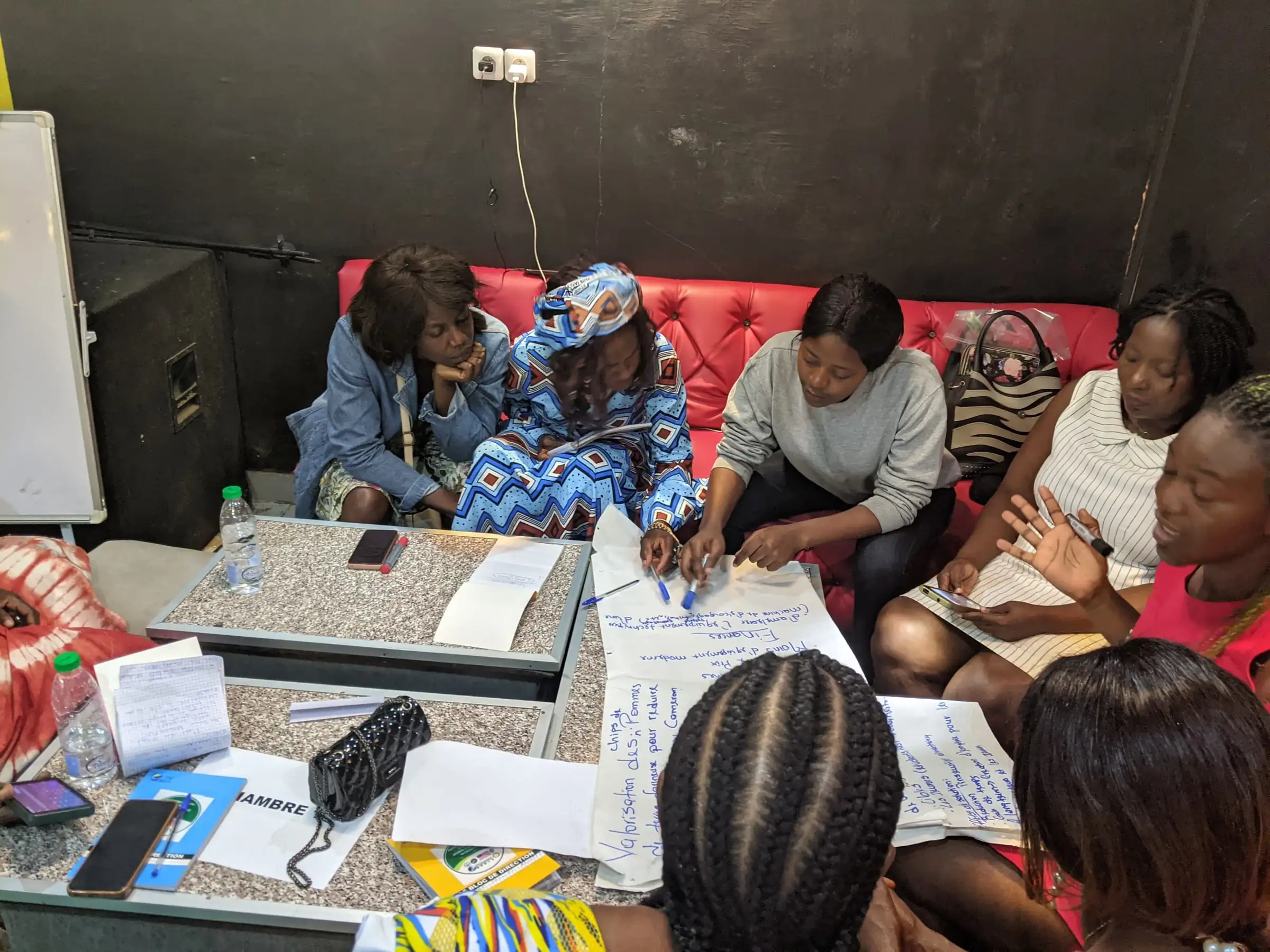 Women work on flip-chart sheets around a low table at a workshop