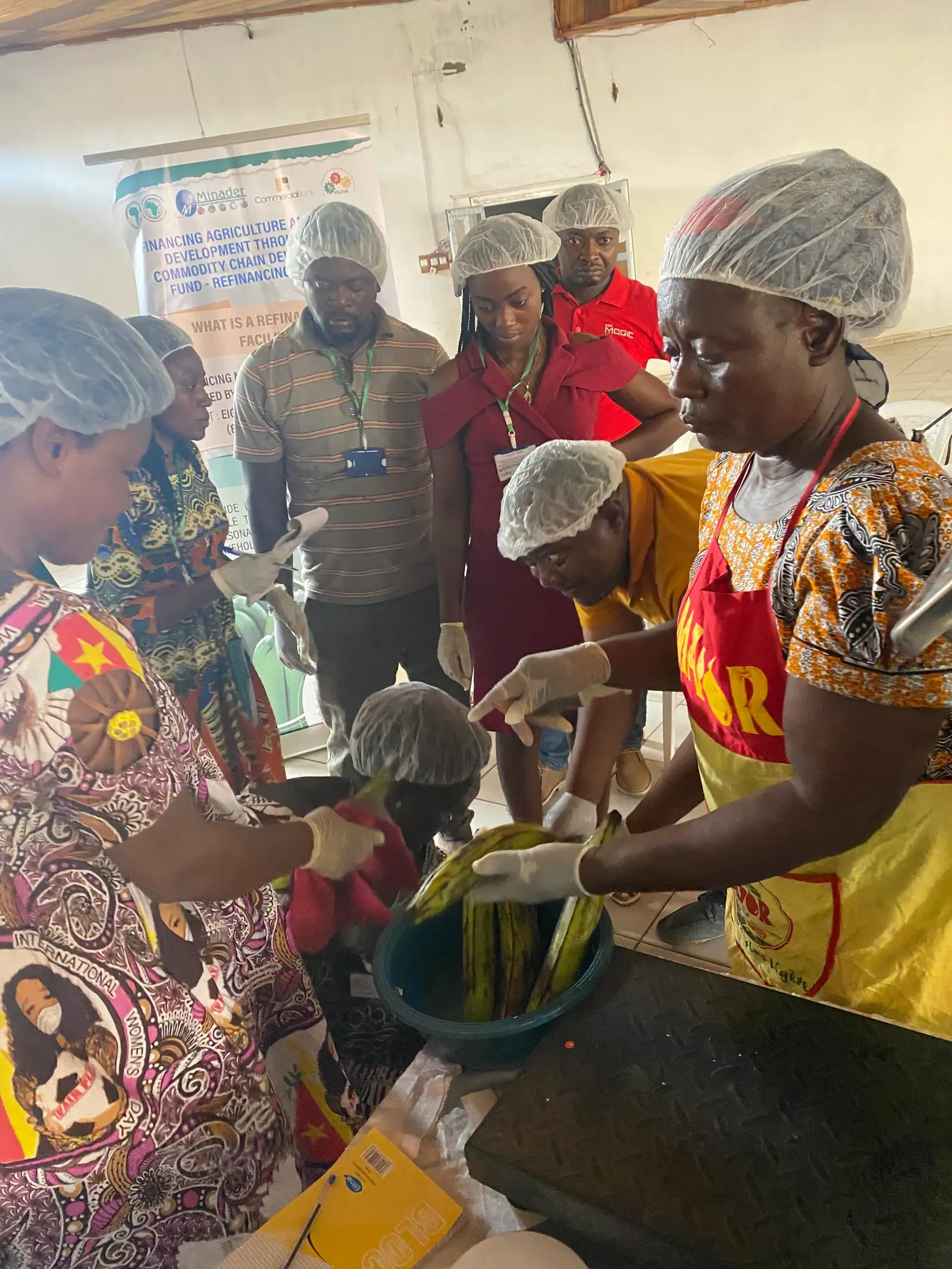 Women in hairnets and aprons peel plantains in a training kitchen